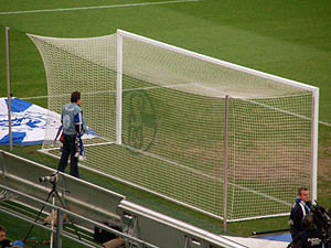 Een doel met FC Schalke 04 logo in de netten verweven en een geconcentreerde supporter