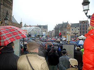 De Grote Markt van Brugge met een menigte enthousiaste koersliefhebbers in de regen met paraplu's.